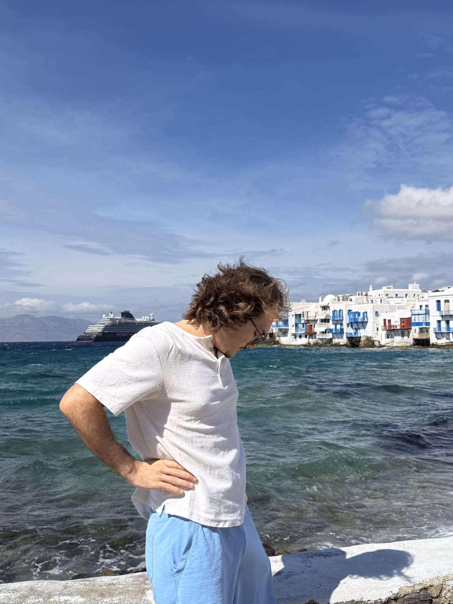 Standing on a whitewashed waterfront in the Greek Cyclades, sea and a cruise ship behind