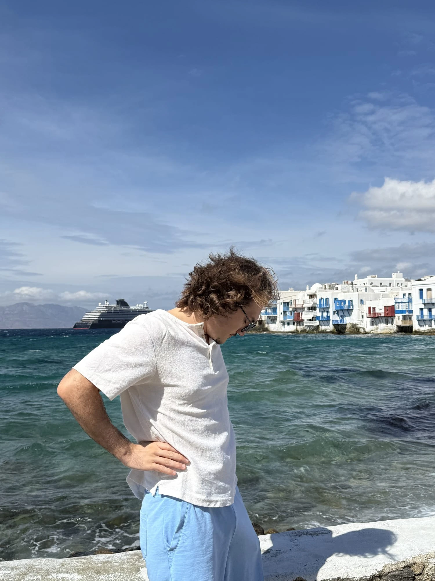 Standing on a whitewashed waterfront in the Greek Cyclades, sea and a cruise ship behind