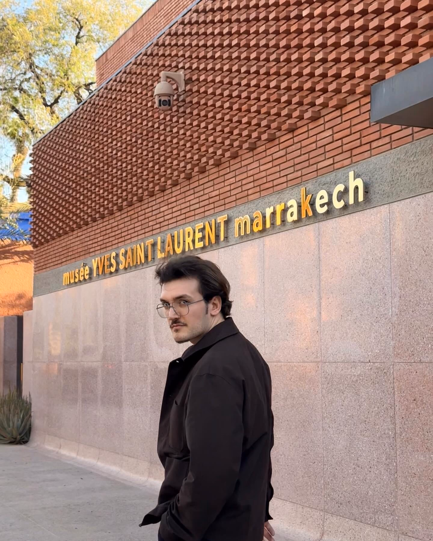 Standing outside the Musée Yves Saint Laurent in Marrakech, the building’s brick facade behind