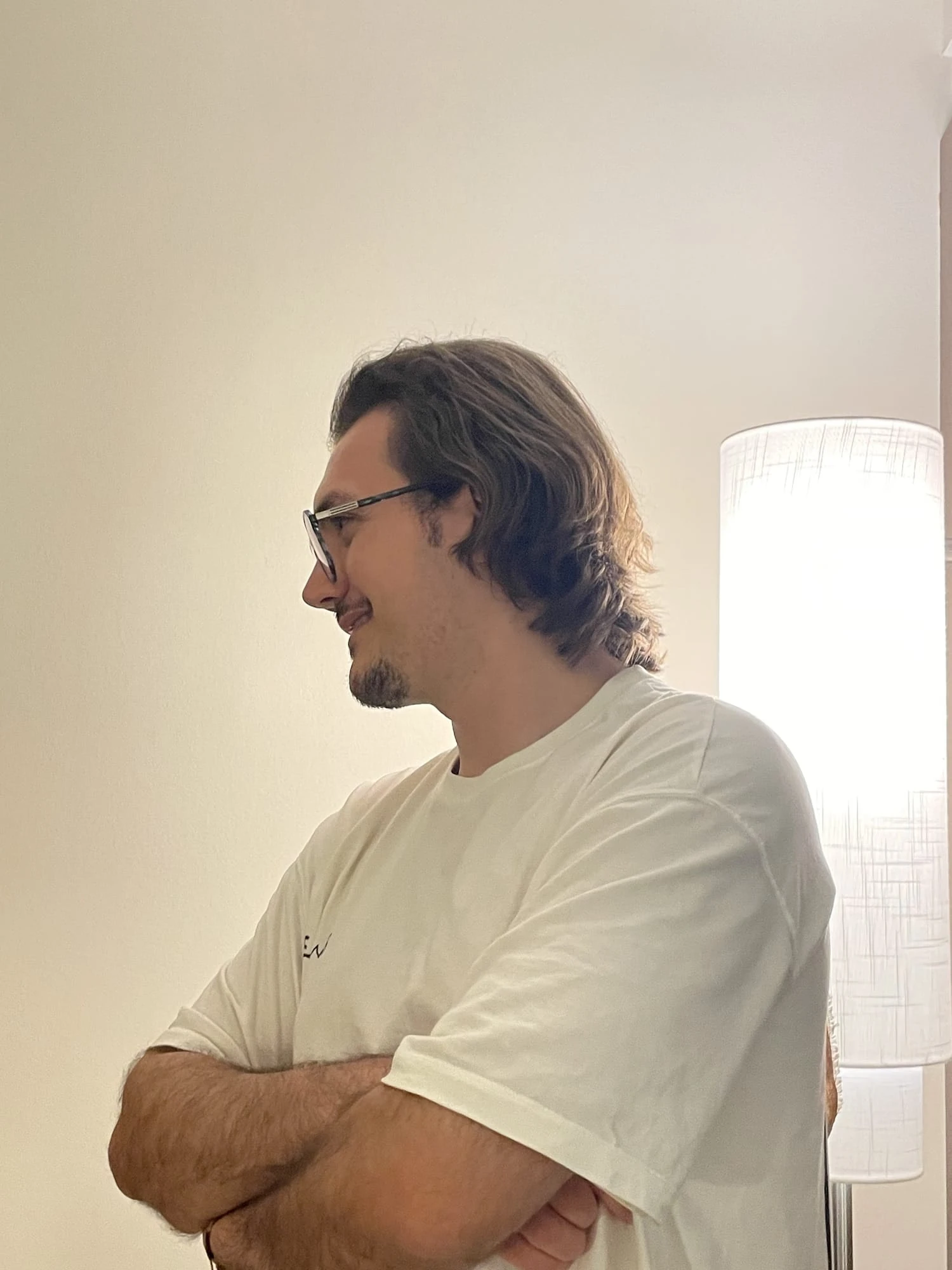 Side profile portrait, arms crossed, indoors by a soft floor lamp